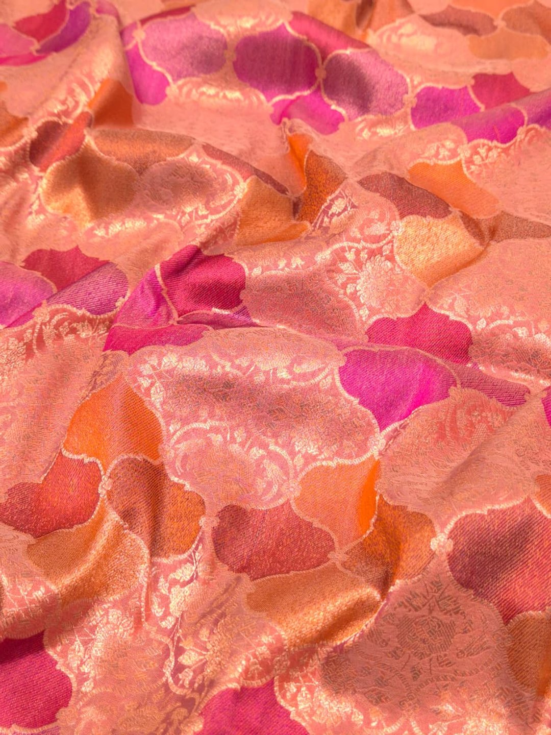 A soft peach and rose-gold base with pink, purple, orange and muted brown accents Mulbari silk Banarasi saree texture detail