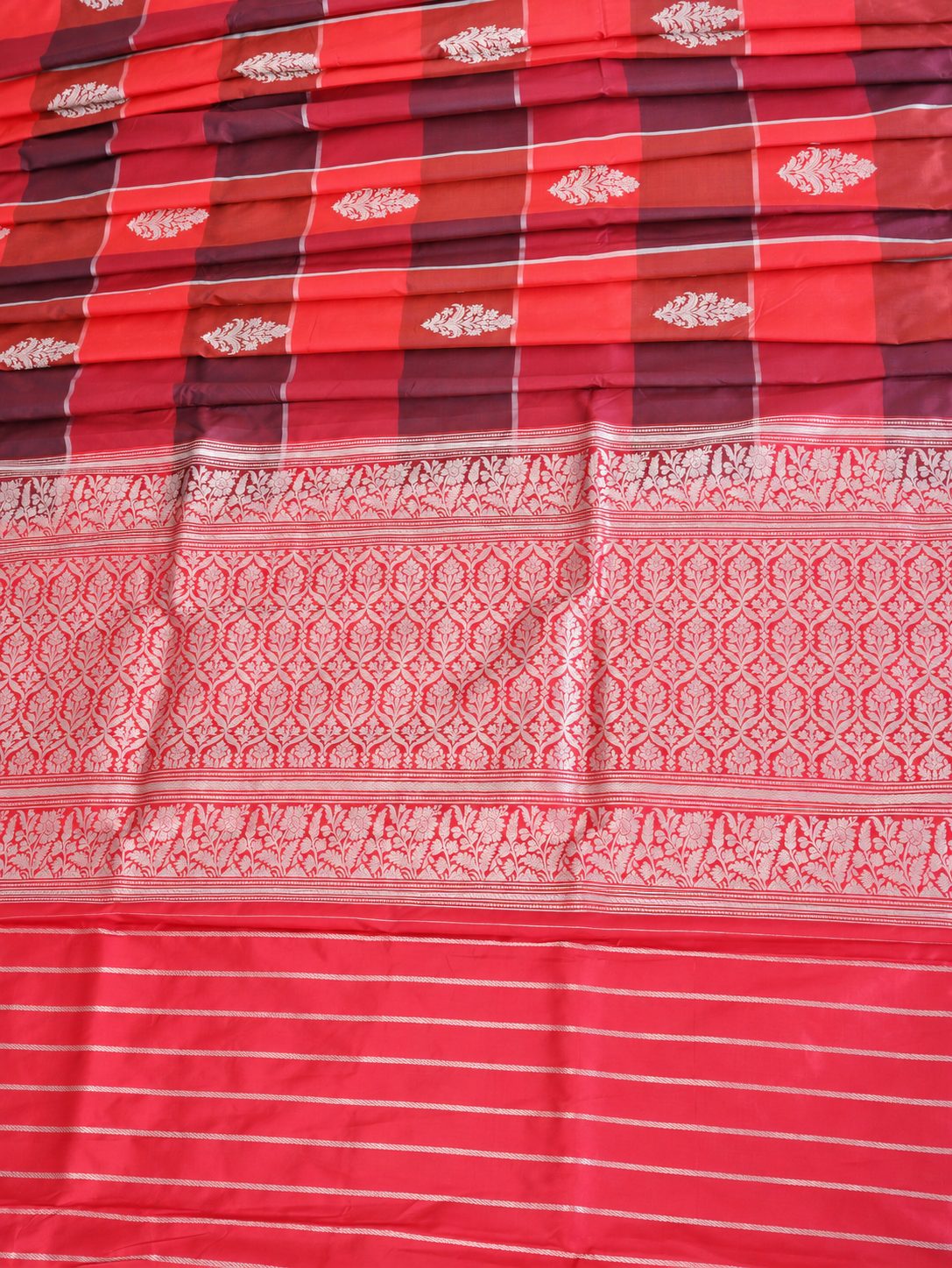 Vibrant coral red and deep plum checks, highlighted with silver-toned woven detailing Katan Silk Banarasi saree texture detail