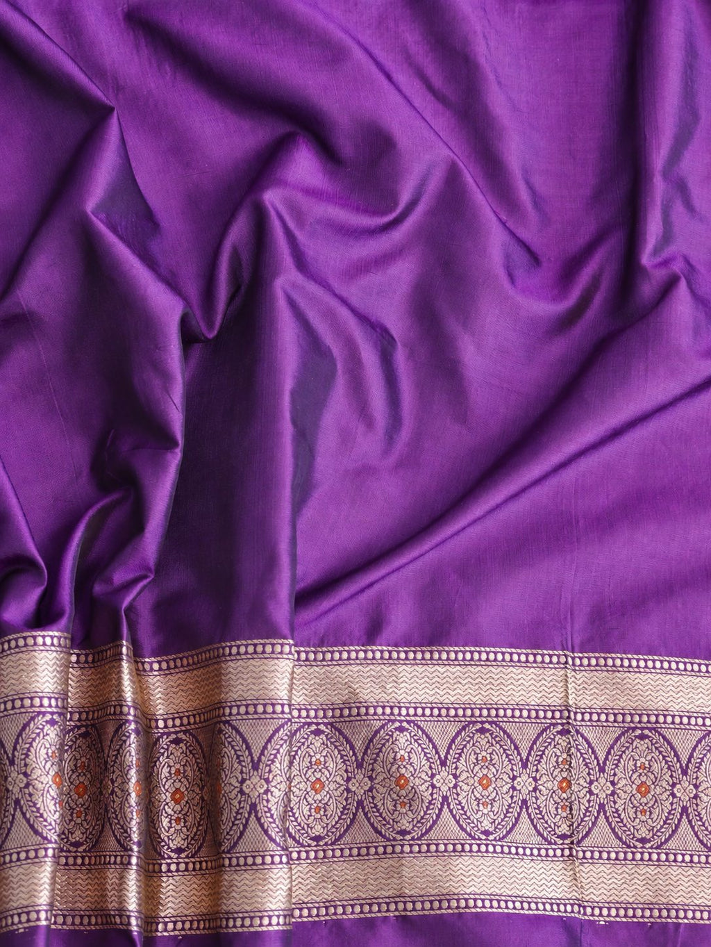 Rich royal purple with pale gold toned zari and vibrant pink and rust-orange floral accents Katan Silk Banarasi saree border closeup