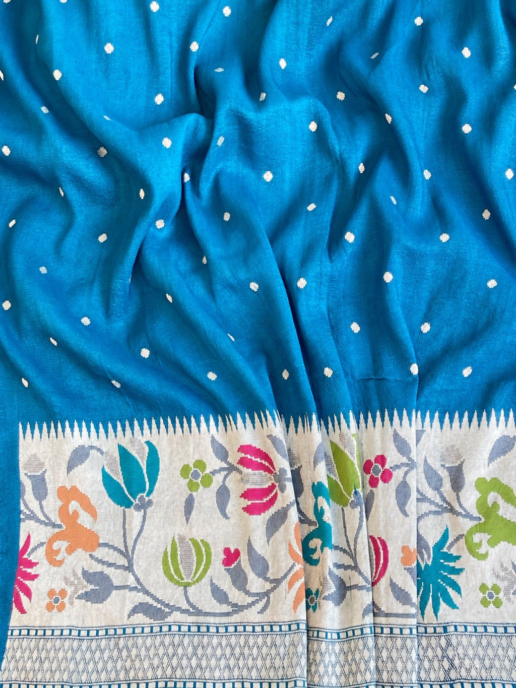 Teal blue with silver-toned zari and pink, peach, green and teal detailing. Tussar Silk Banarasi saree front drape view