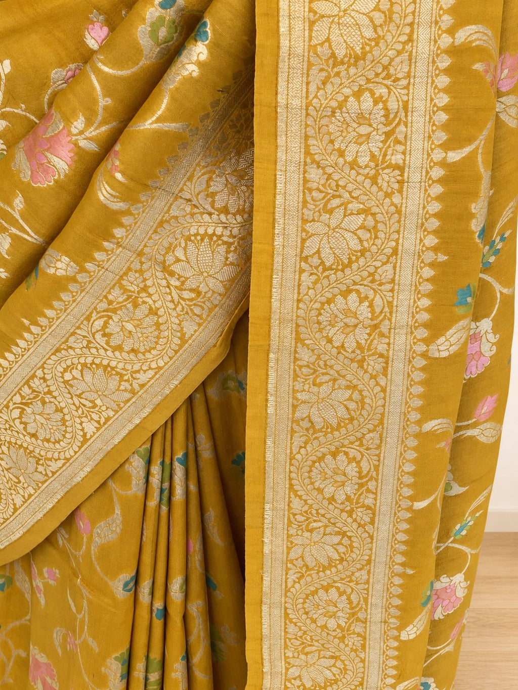 Mustard yellow with gold-toned zari and pastel pink, teal and green detailing Tussar Silk Banarasi saree border closeup